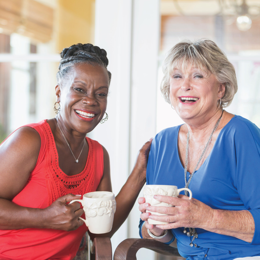 Black senior woman and white senior woman having coffee in a resident's home